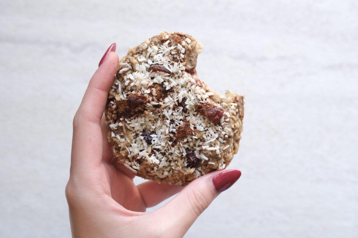 A hand holding a Cran, Ban & Co cookie with a bite taken out
